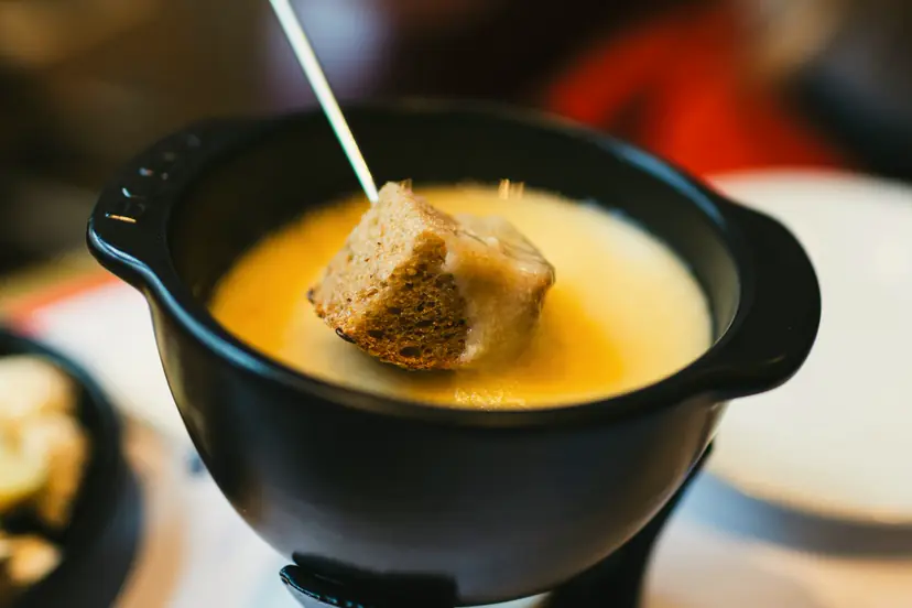 Morceau de pain trempé dans une fondue au fromage